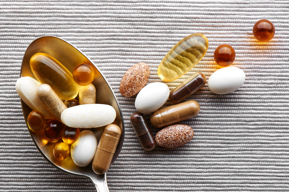 Wholesale vitamins. A spoon on a table with a selection of vitamins